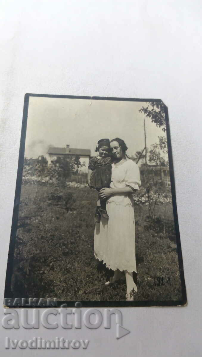 Снимка Млада жена с момиченце на ръце в двора