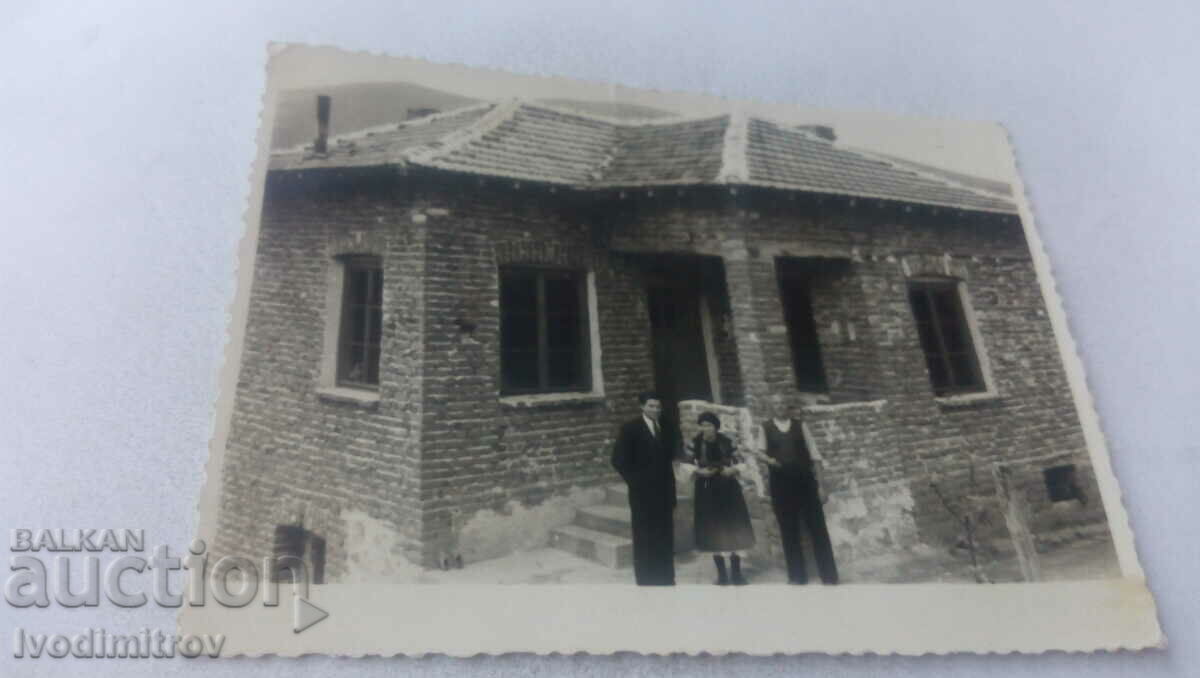 Foto Doi bărbați și o femeie în fața unei case nou construite