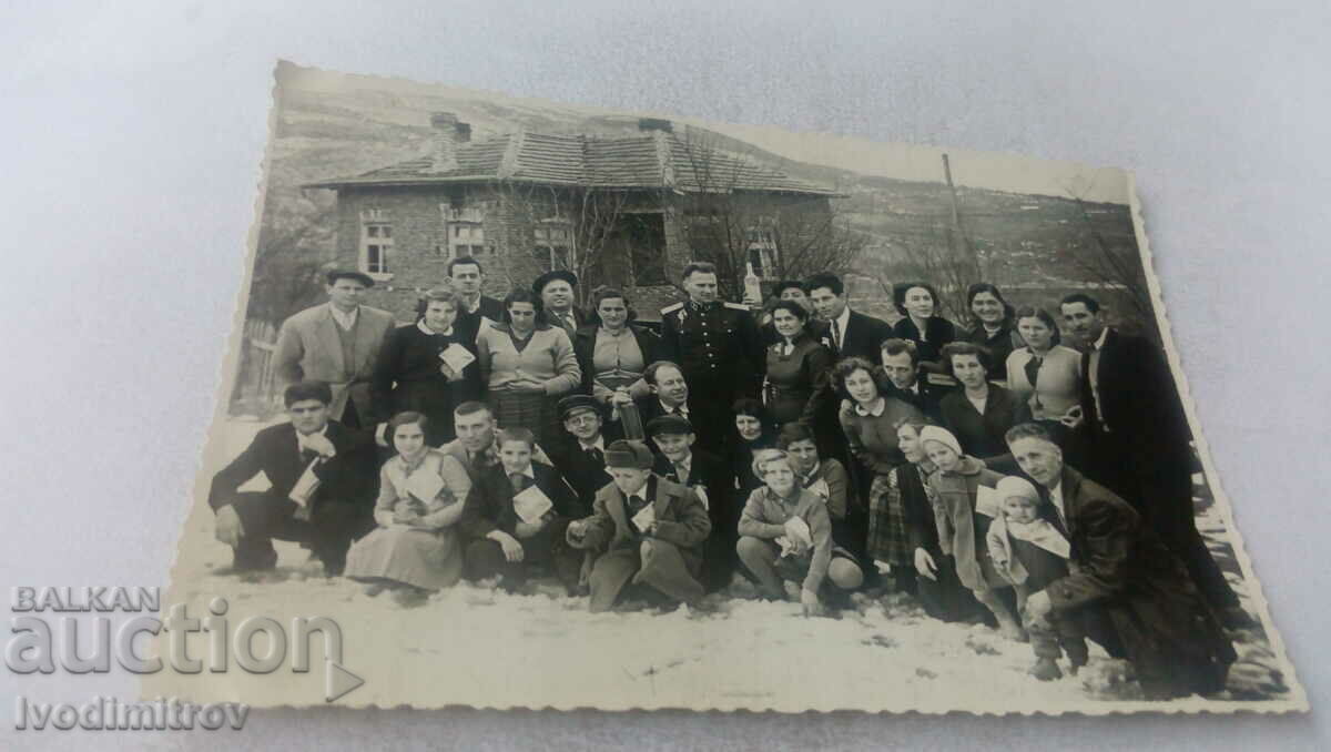 Ofițer foto bărbați femei și copii în fața unei case iarna