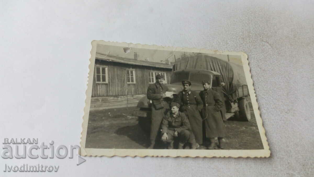 Photo Four soldiers in front of a vintage military truck