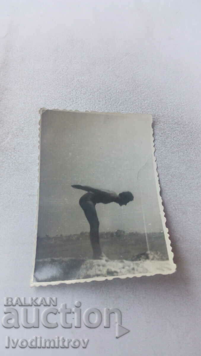 Fotografie Un bărbat sare de pe o stâncă în mare