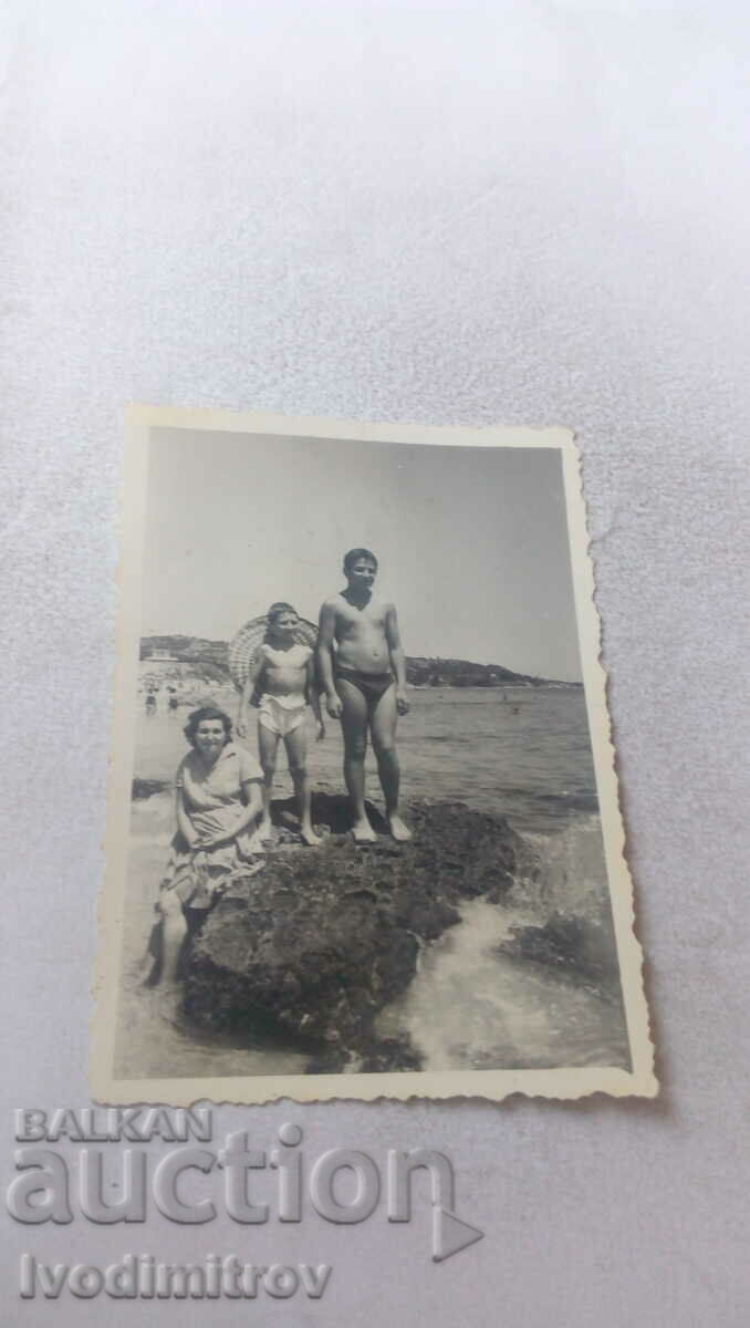 Φωτογραφία Γυναίκα και δύο αγόρια σε έναν βράχο στην ακτή