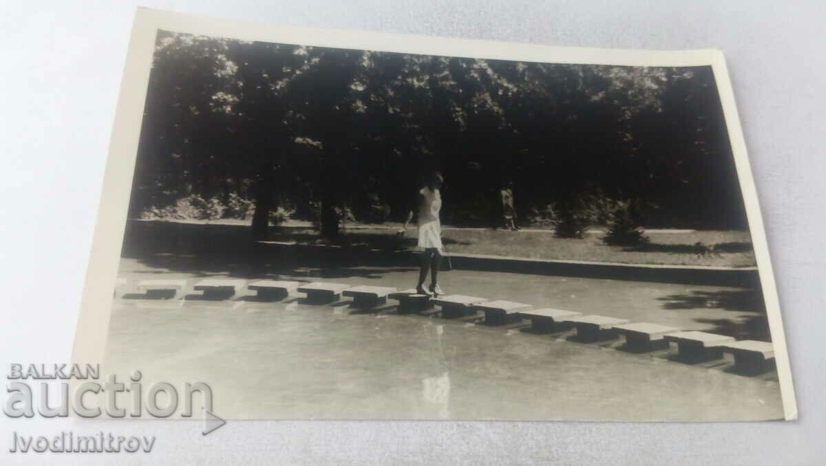 Φωτογραφία Μια νεαρή γυναίκα περπατά πάνω σε πλακάκια σε ένα σιντριβάνι