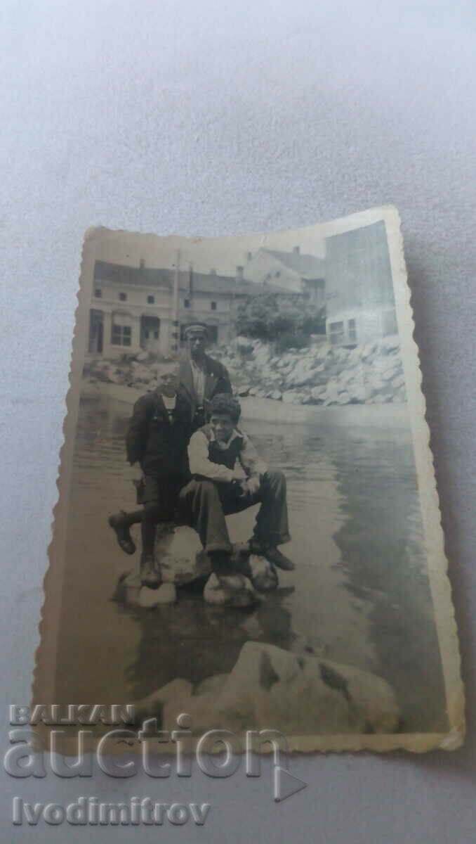 Foto Trei tineri pe pietre în râu