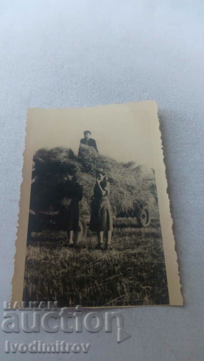 Photo A man and two women with a wagon loaded with hay