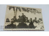 Снимка Офицер с ордени разговаря с мъж и жена на маса
