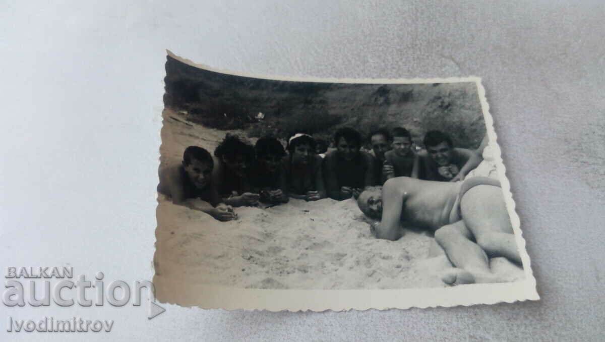 Fotografie Bărbați și băieți întinși pe nisip pe plajă