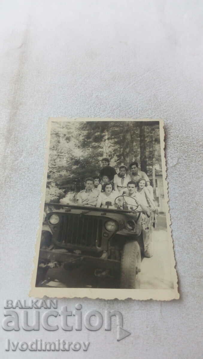 Photo Young men and women with a vintage jeep on a walk in the forest
