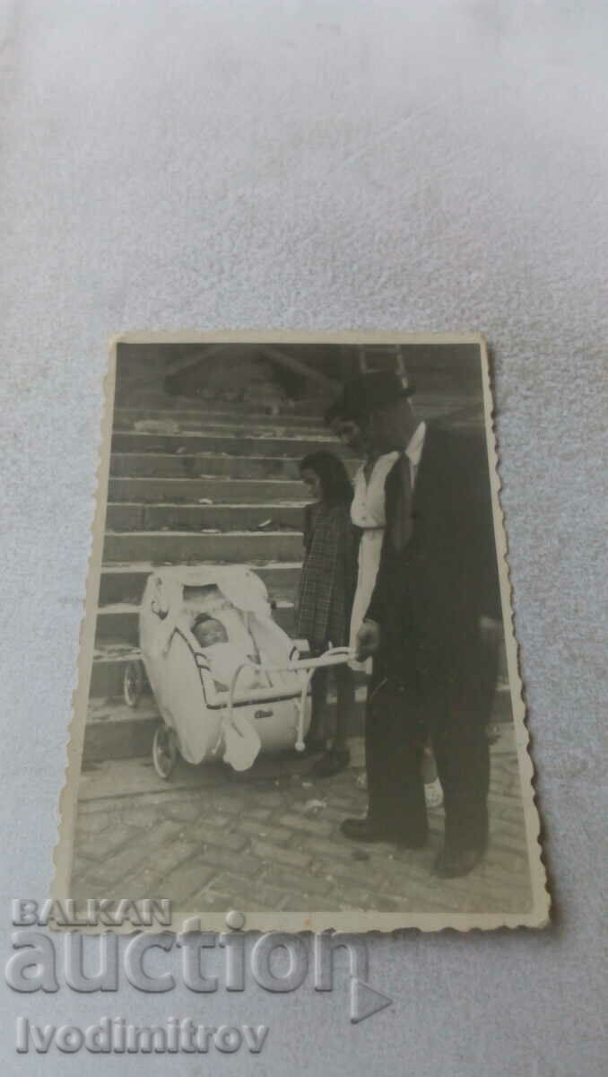 Κα Άνδρας γυναίκα κορίτσι μωρό στο ρετρό καρότσι μπροστά από τις σκάλες