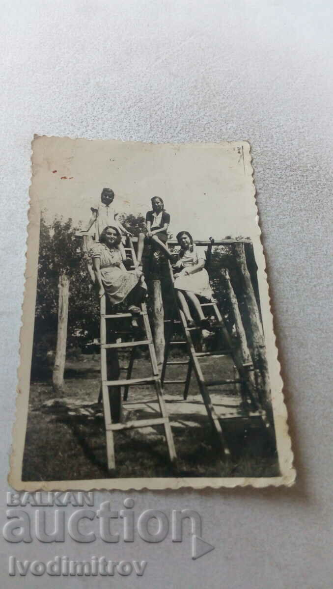 Fotografie Patru fete tinere pe un cadru de cățărat din lemn