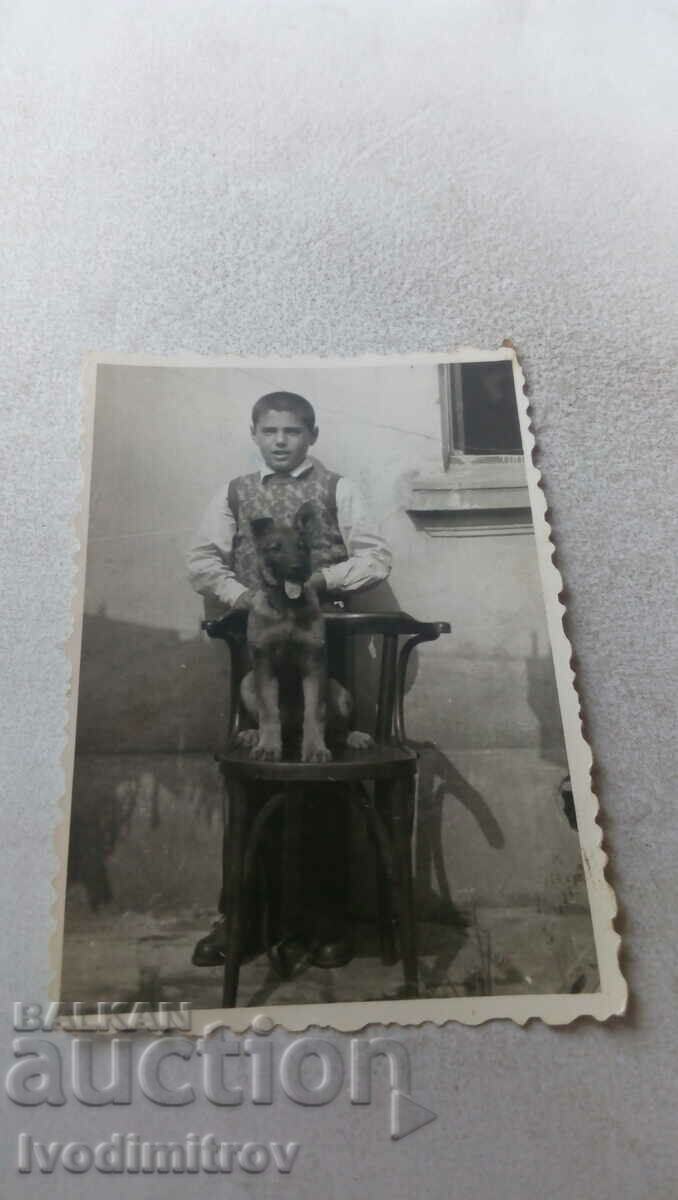 Φωτογραφία Ένα αγόρι και ένα μικρό σκυλί σε μια ξύλινη καρέκλα