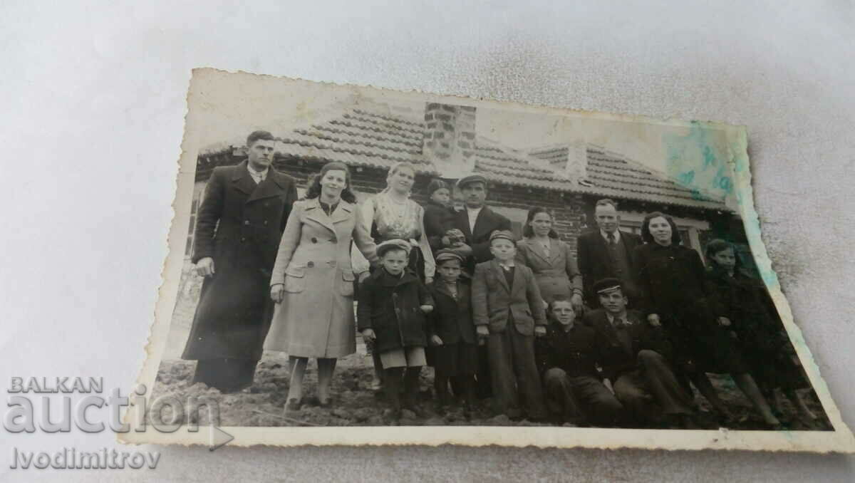 Photo Men, women and children in front of a newly built house