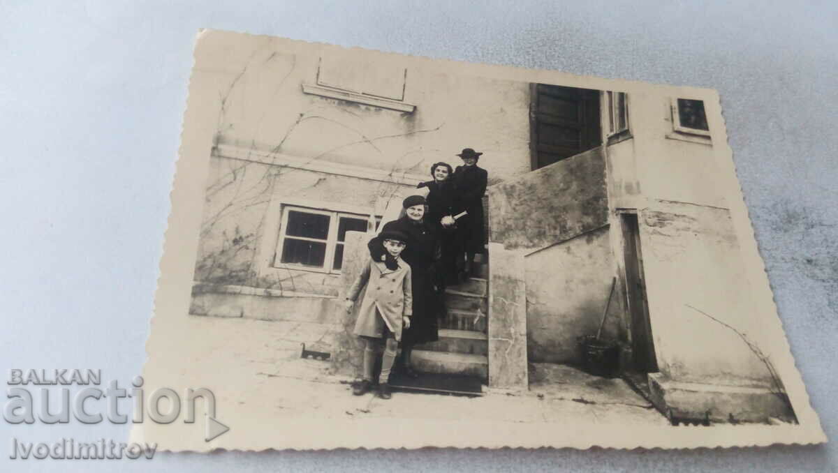 Foto Trei femei și un băiat pe scări în fața intrării unei case