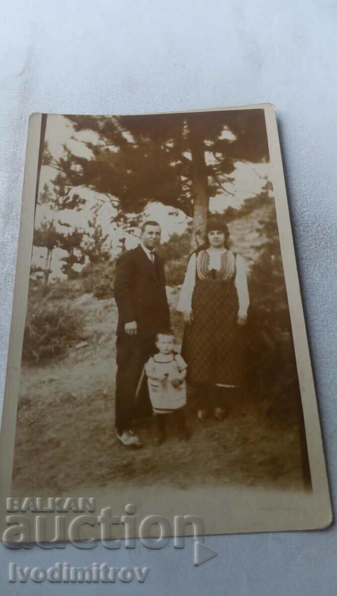 Photo A man, a little boy and a woman in folk costume in the forest