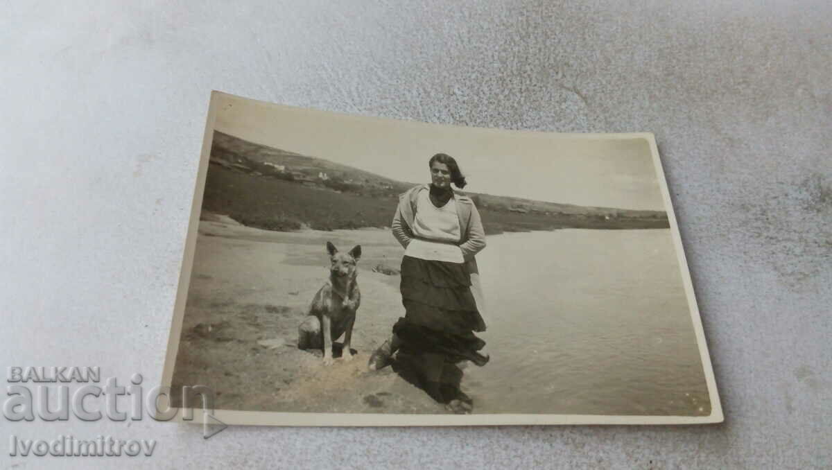 Fotografie O tânără cu un câine de rasă de lup lângă râu