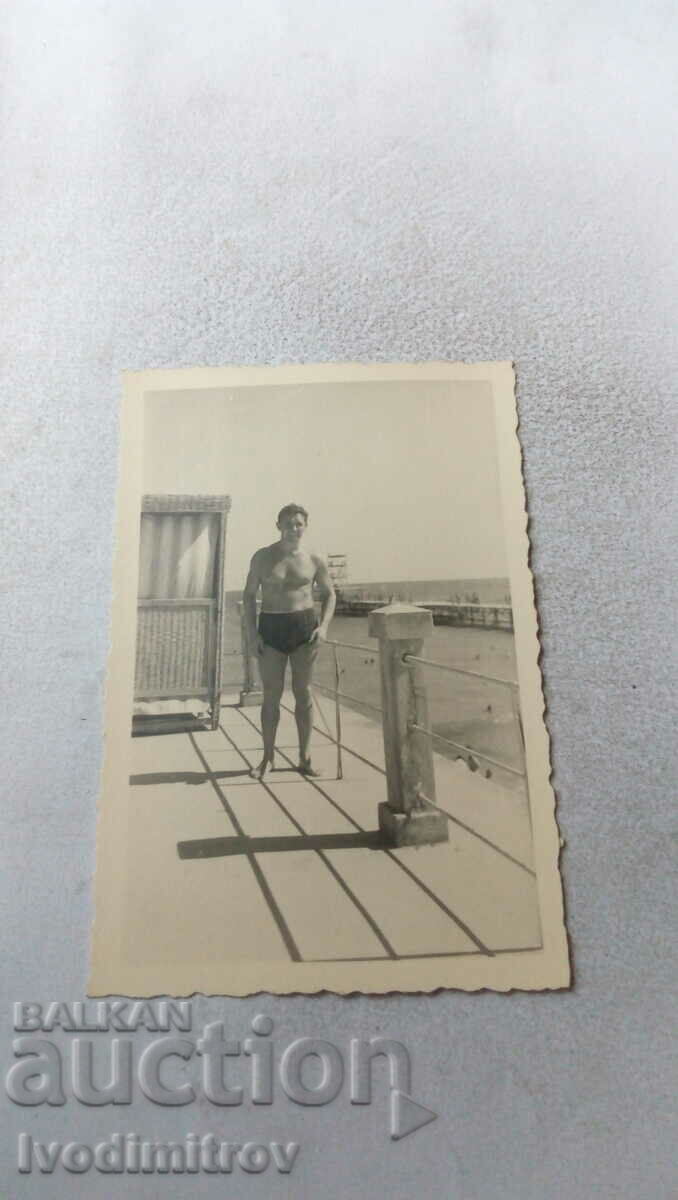 Foto Bărbat în costum de baie pe o platformă de lemn pe plajă