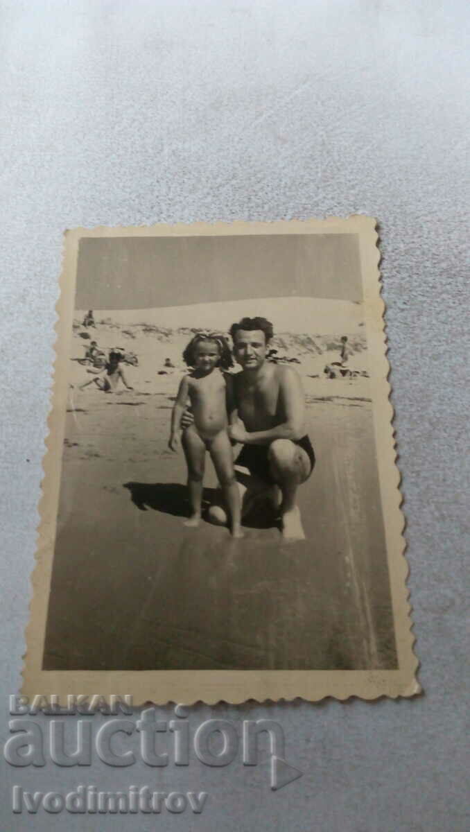 Photo A man and a little girl on the beach