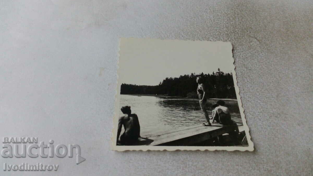Photo A young man and a young woman on a wooden platform by a lake