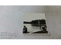 Φωτογραφία Ένας νεαρός άνδρας και μια νεαρή γυναίκα σε μια ξύλινη πλατφόρμα δίπλα σε μια λίμνη