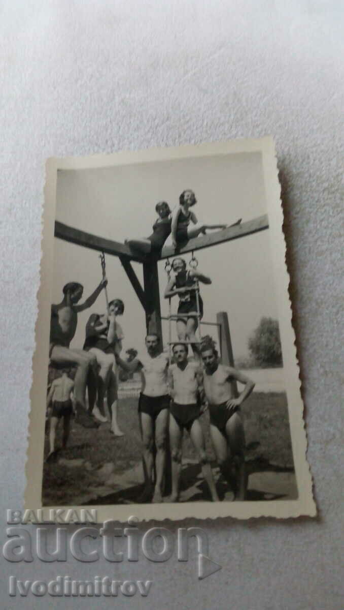 Photo Young men and women in swimsuits on gymnastic equipment