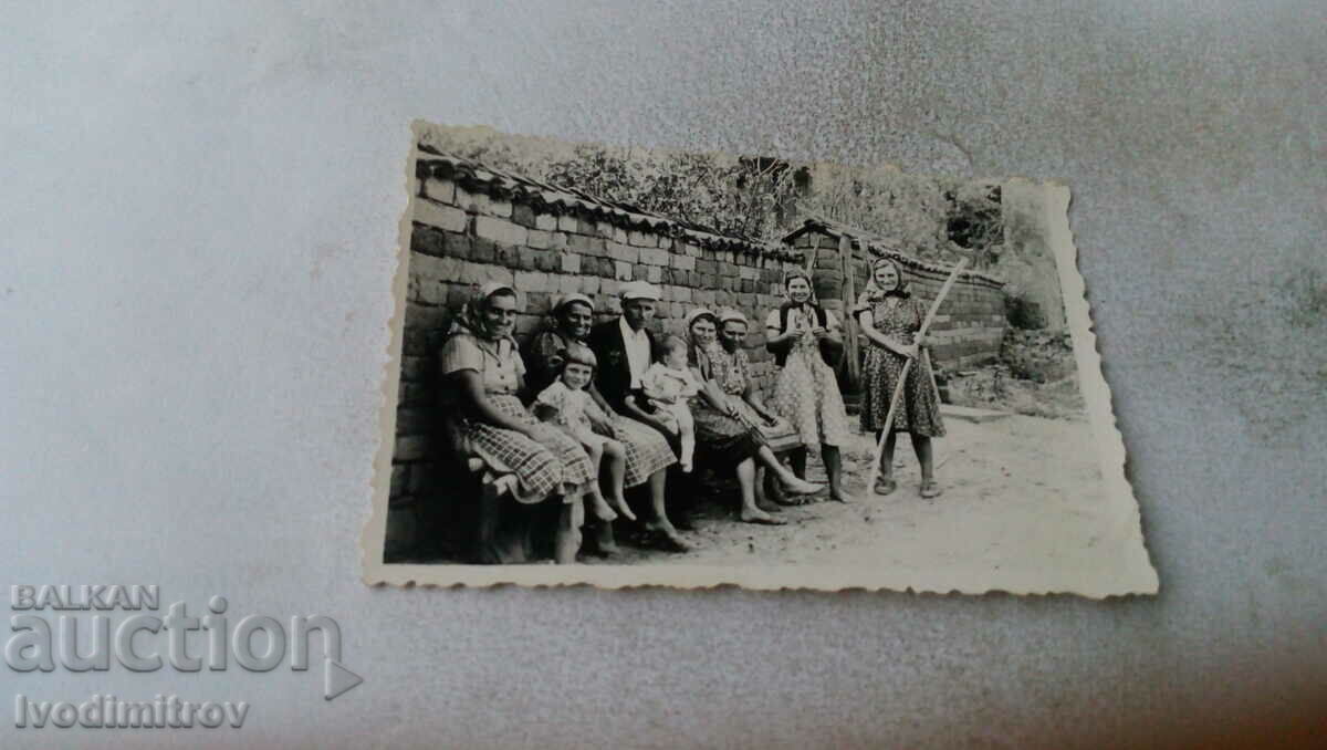 Fotografie Bărbați, femei și copii pe o bancă lângă un gard