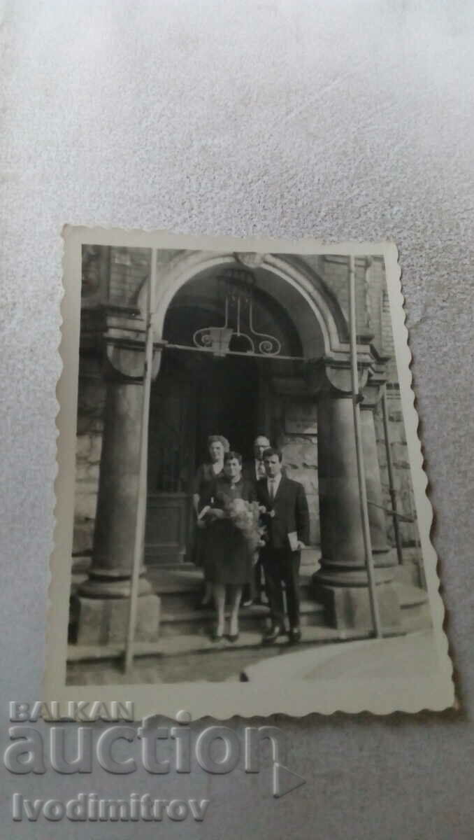 Foto Doi bărbați și două femei în fața intrării unei biserici
