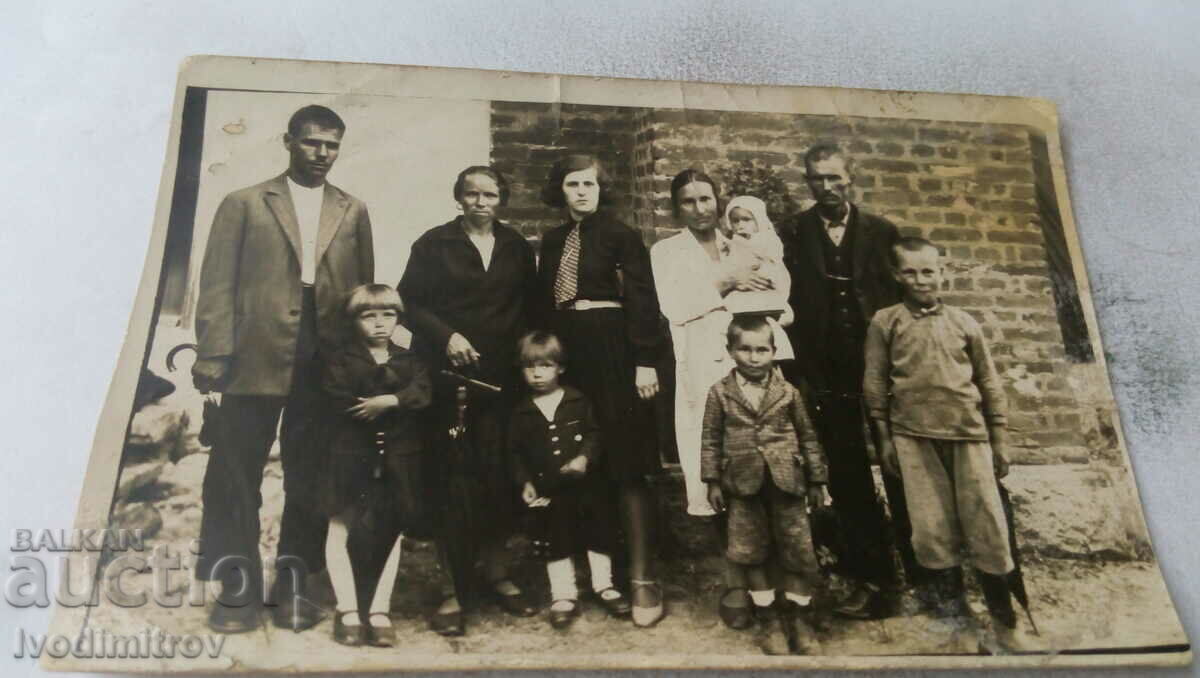 Photo Men women and children in front of a house