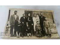 Foto Bărbați, femei și copii în fața unei case
