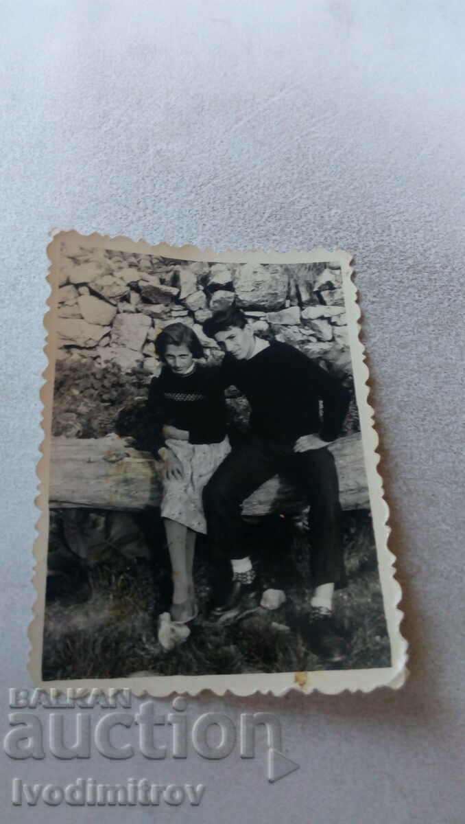 Φωτογραφία Ένας νεαρός άνδρας και ένα κορίτσι σε έναν ξύλινο πάγκο