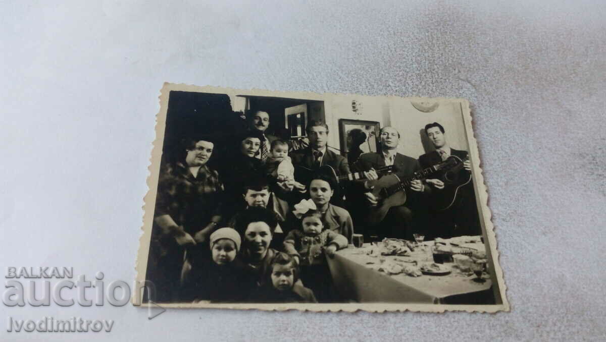 Photo Women, children and three men with guitars around a table