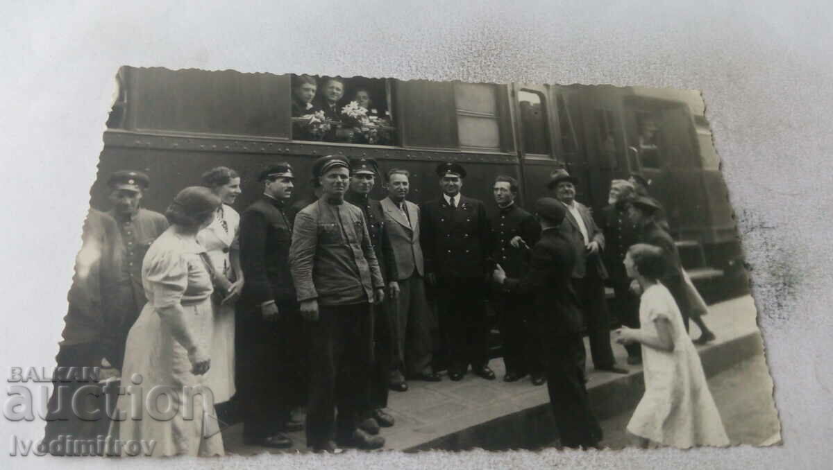 Photo Railwaymen and passengers past passenger cars