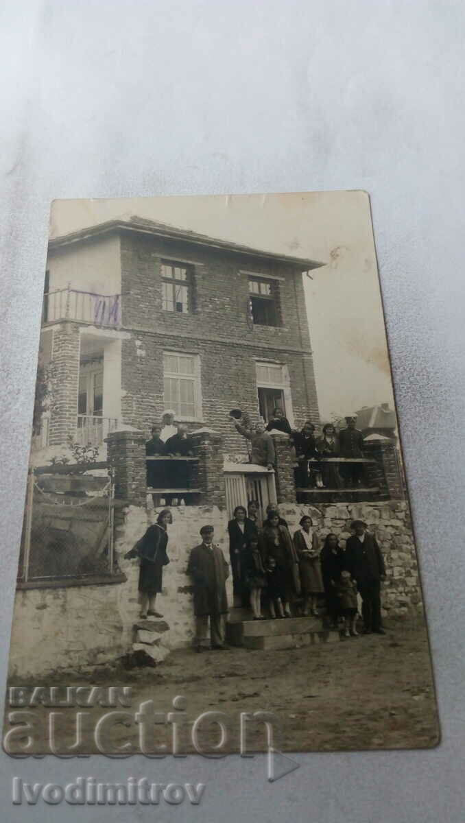 Photo Men, women and children in front of a newly built three-story house