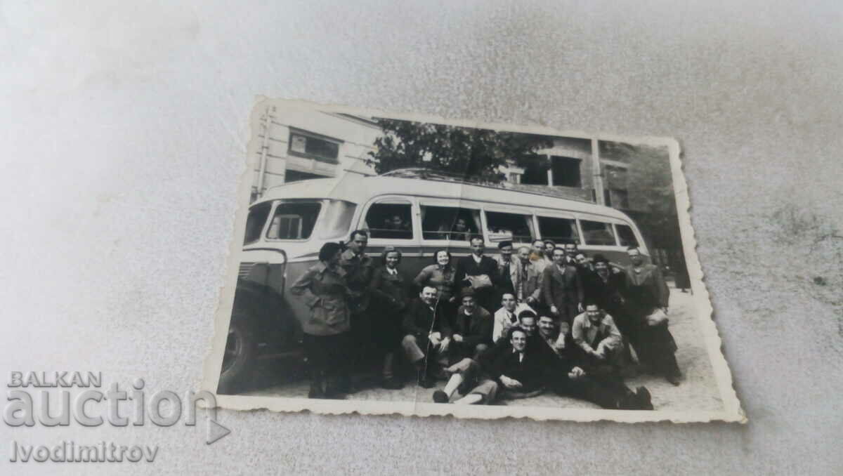 Photo Men and women in front of a vintage bus