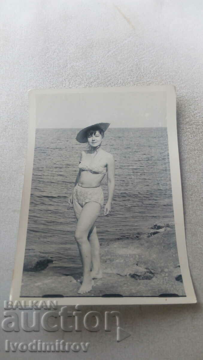 Foto Fată tânără în costum de baie de epocă pe o stâncă lângă mare