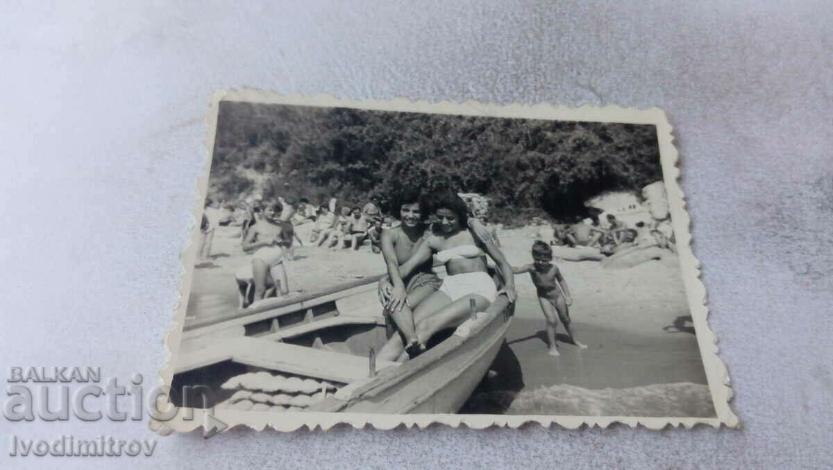 Εικόνα Δύο γυναίκες σε μια βάρκα και ένα αγοράκι στην ακτή