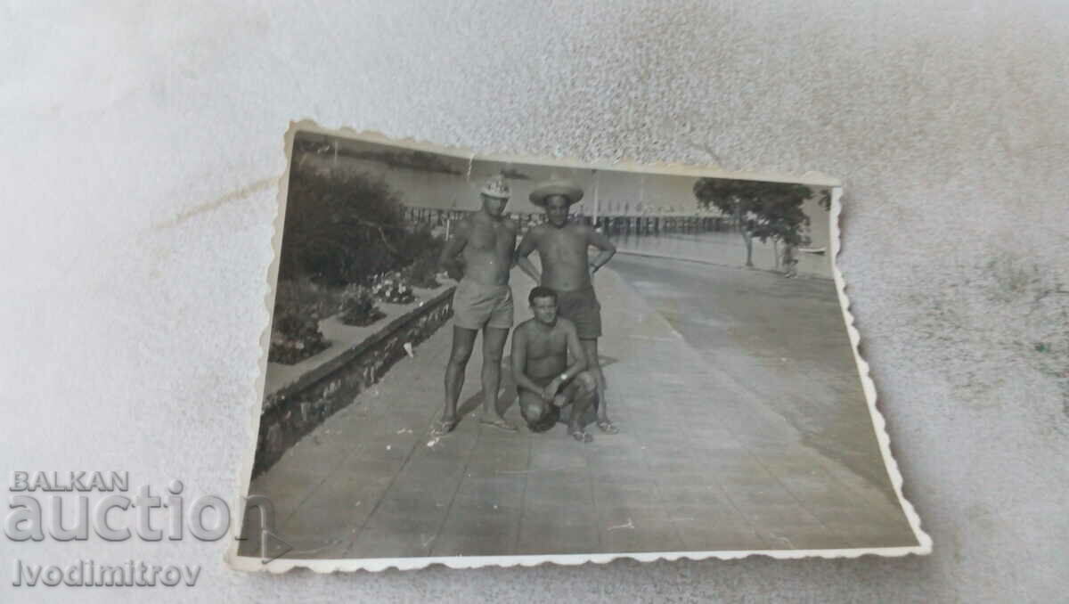 Foto Trei bărbați în pantaloni scurți pe o promenadă