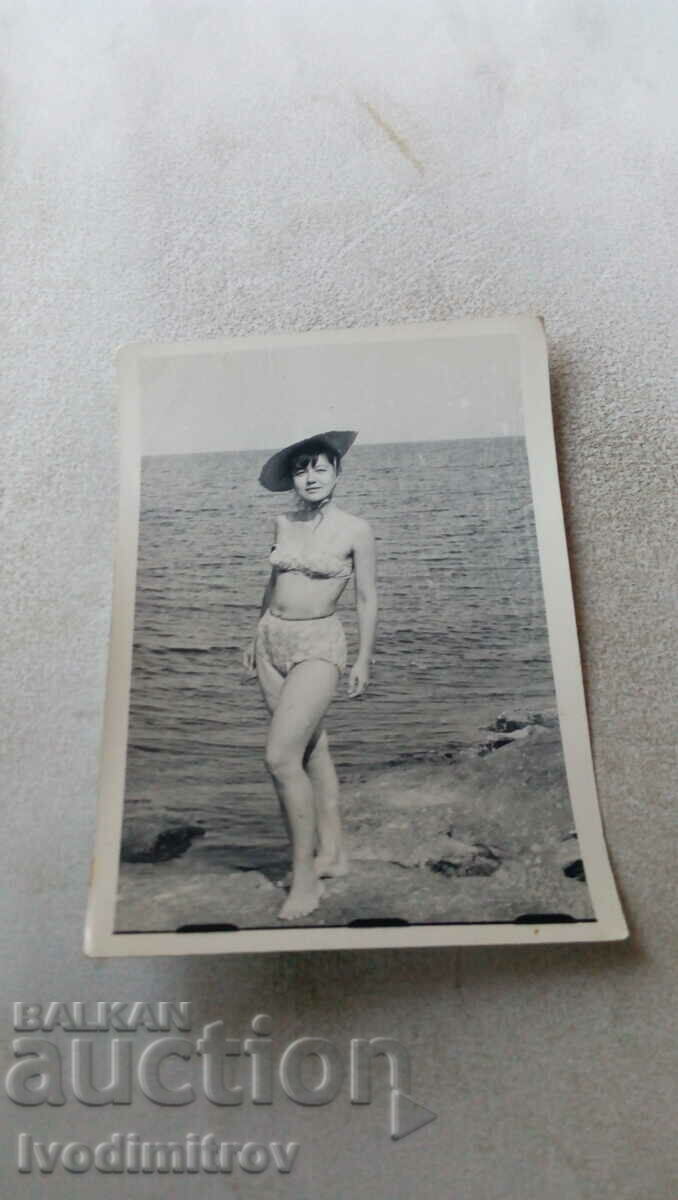 Fotografie Tânără cu o pălărie pe o stâncă lângă mare