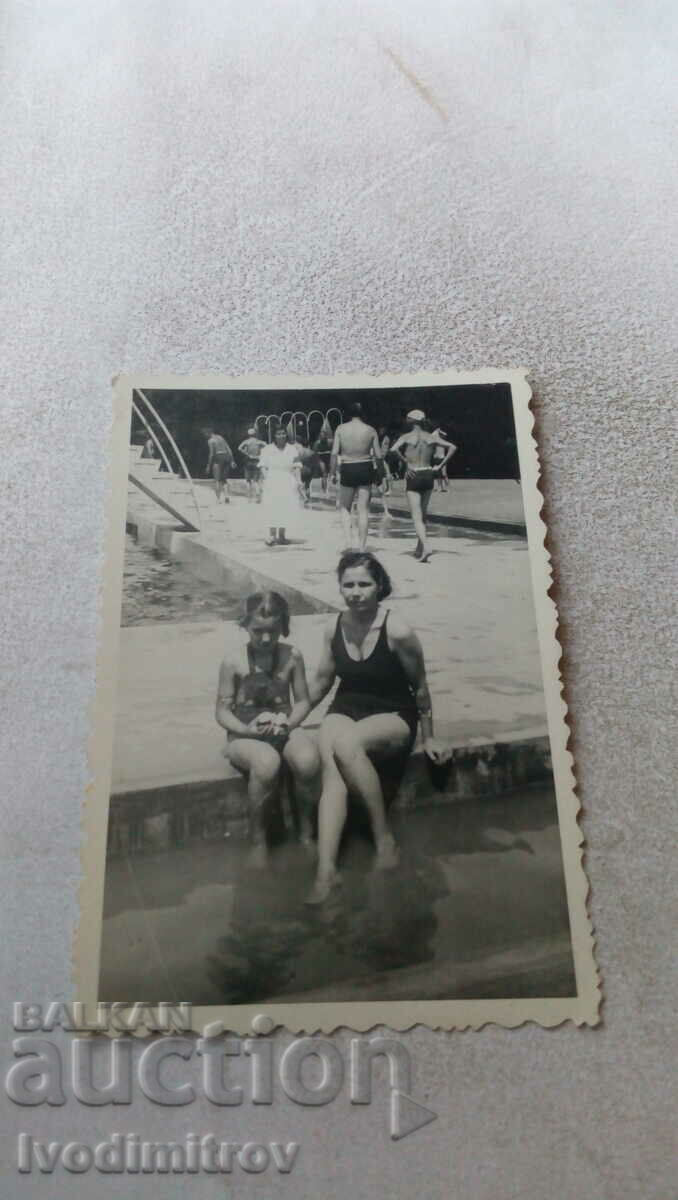 Photo A woman and a girl sit by a pool