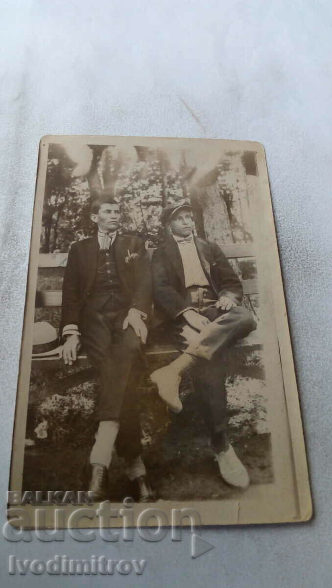 Photo Two young men sitting on a wooden bench