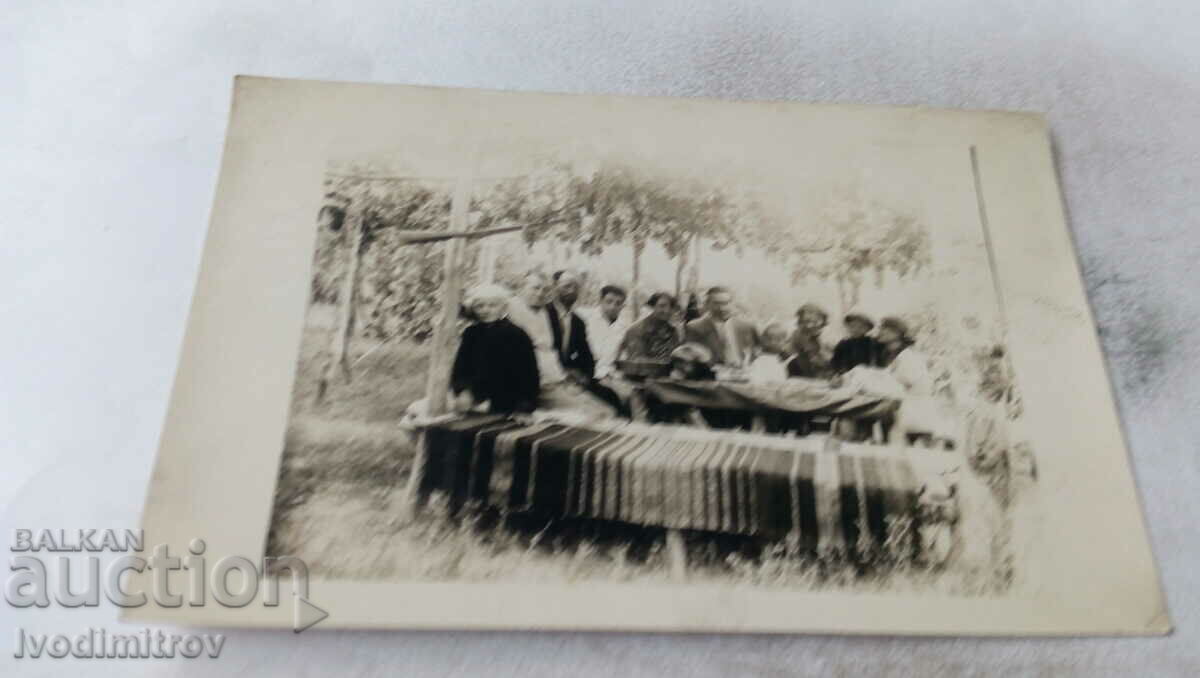 Снимка Мъже жени и деца на маса под асмата в двора