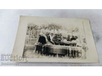 Foto Bărbați, femei și copii la o masă sub asma din curte