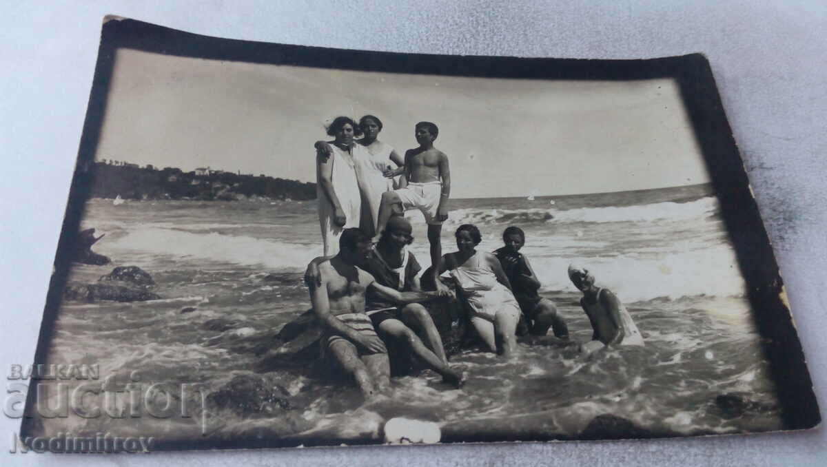 Photo Young men and women in vintage swimsuits on a stone in the sea