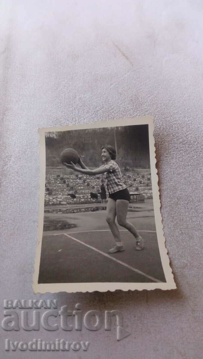 Foto Fată tânără cu o minge de baschet pe un teren