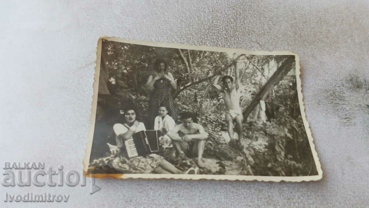 Foto Bărbați în pantaloni scurți și femei cu acordeon în pădure