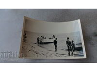 Photo Young men on the seashore next to a wooden boat OTTER