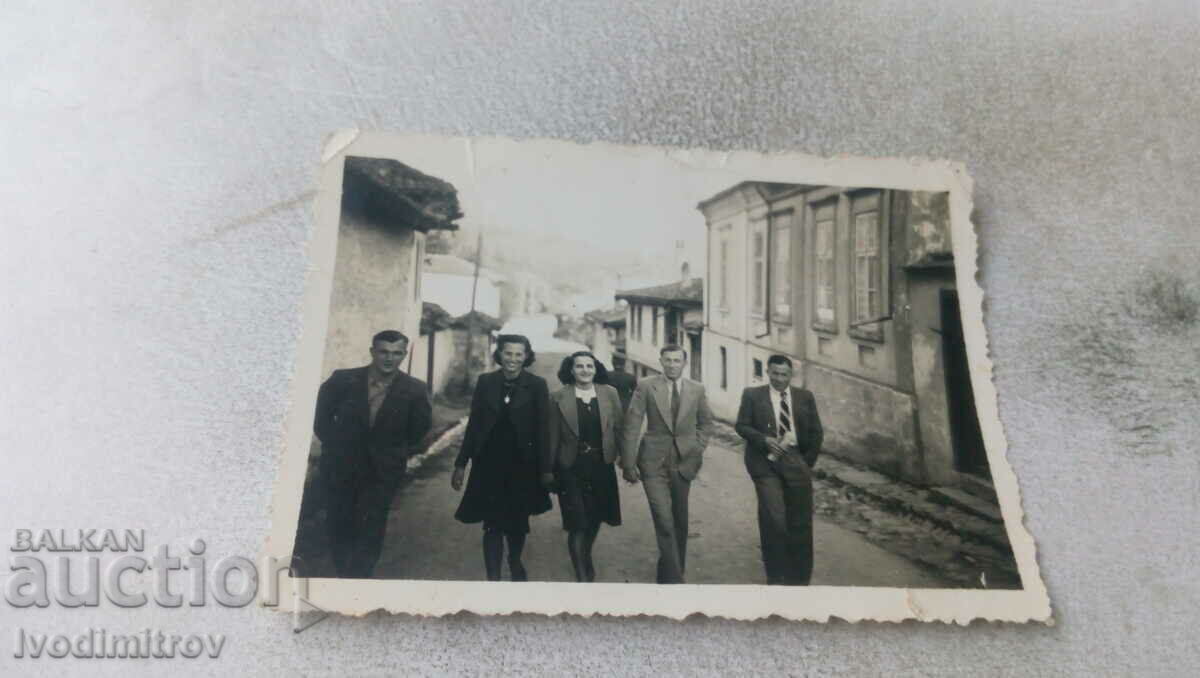 Foto Trei bărbați și două tinere care merg pe stradă