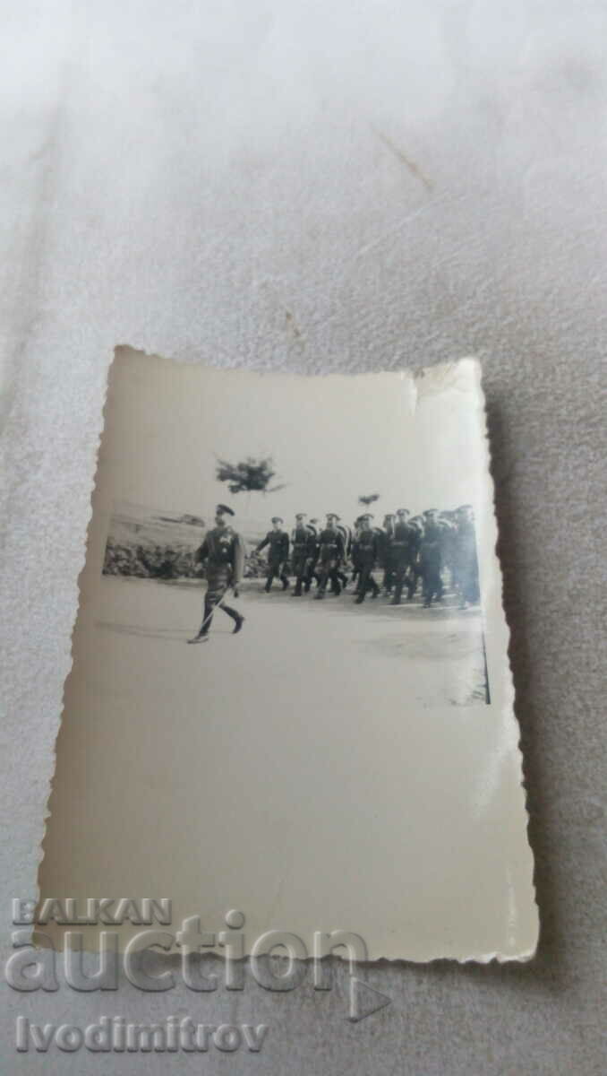 Αξιωματικός φωτογραφιών και στρατιώτες που βαδίζουν κατά μήκος του δρόμου