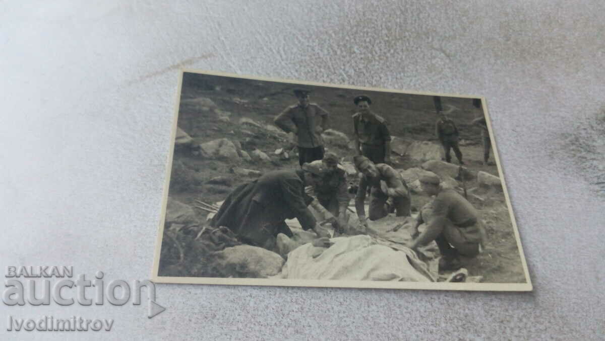 Φωτογραφία Αξιωματικοί και στρατιώτες απλώνουν μια κουβέρτα στο έδαφος