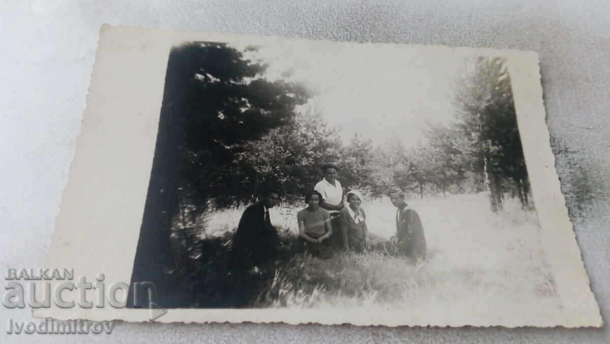 Φωτογραφία Τρεις νεαροί άνδρες και δύο κορίτσια σε ένα λιβάδι στο δάσος