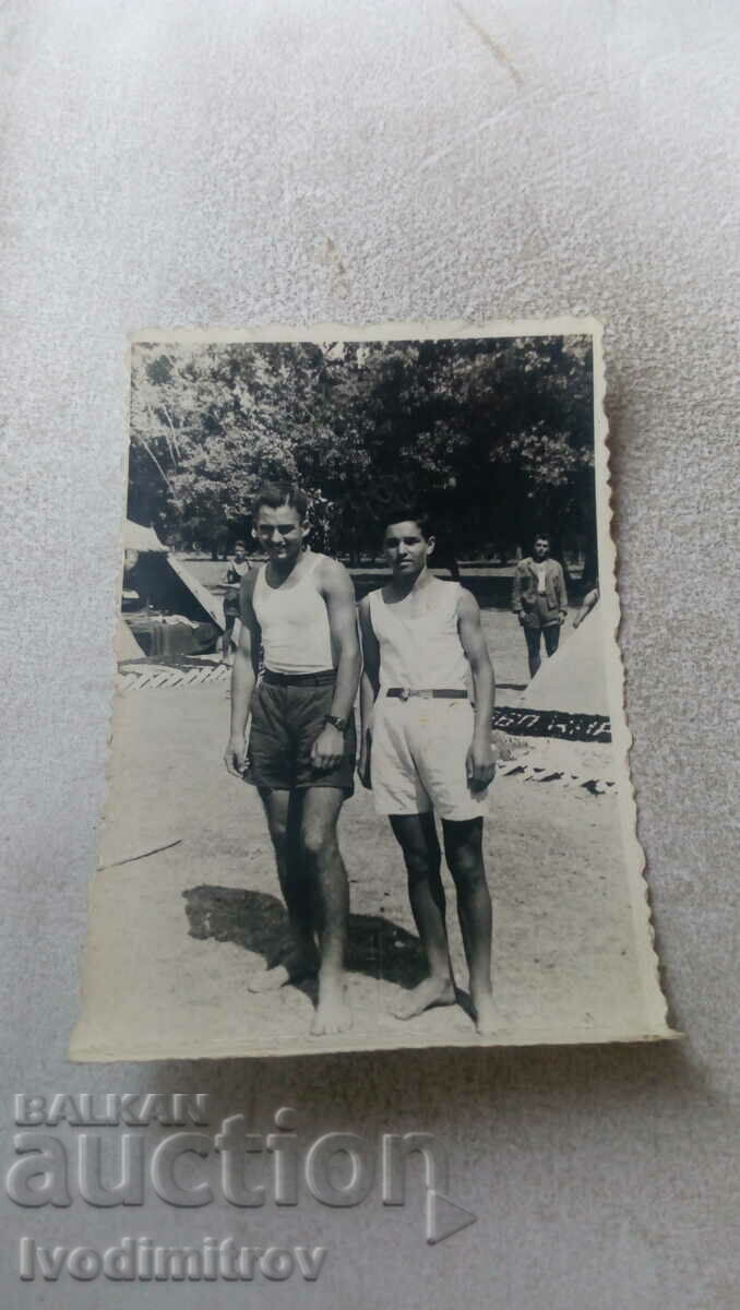 Mrs. Two young men in shorts in front of a paramilitary camp